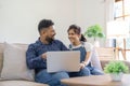 Happy indian family couple using laptop looking at computer laptop sitting on sofa together relaxing at home Royalty Free Stock Photo