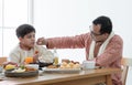 Happy Indian family enjoy eating food with hands, South Asian father wipe his little boy mouth with love and care Royalty Free Stock Photo