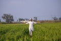 Happy indian farmer walking and spreading his arms in his growing fields