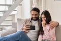 Happy indian father with teenage daughter having fun using phone at home. Royalty Free Stock Photo