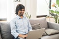 Cheerful optimistic young indian man wearing casual shirt using laptop Royalty Free Stock Photo