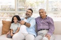 Happy Indian great grandpa, granddad and grandkid girl watching TV