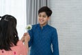 Happy Indian handsome boy receiving small white flower for surprise gift from little cute girl, children wear traditional clothing Royalty Free Stock Photo