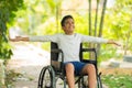 Happy indian kid with disability feeling fresh air by stretching hands sitting on wheelchair at park - concept of Royalty Free Stock Photo