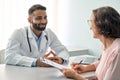 Happy Indian male doctor consulting senior patient filling medical form. Royalty Free Stock Photo