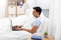 Happy indian man with laptop in bed at home Royalty Free Stock Photo