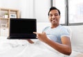 Happy indian man showing his laptop in bed at home Royalty Free Stock Photo