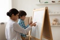 Happy Indian mom and small son draw on whiteboard Royalty Free Stock Photo