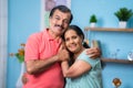 Happy Indian senior couple closely standing by embracing each other by looking camera at home - concept of family Royalty Free Stock Photo