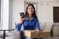 Happy Indian shopper girl holding mobile phone and cardboard box Royalty Free Stock Photo