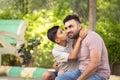 Happy indian son kissing his father while sitting at park - concept of affectionate, family relationship and joyful. Royalty Free Stock Photo