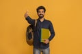 Happy indian student guy with backpack and notebooks showing thumbs up gesture Royalty Free Stock Photo