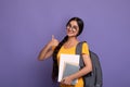 Happy indian student wearing eyeglasses holding notebooks showing thumbs up