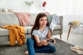 Happy Indian teenager with joystick playing online computer games in messy room during covid lockdown