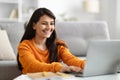 Happy indian woman digital nomad working on laptop, home interior Royalty Free Stock Photo