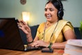 Happy Indian woman with headphones busy talking in video call on laptop - concept of online chat, distance webinar Royalty Free Stock Photo