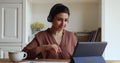 Happy Indian woman in headphones start videoconference on digital tablet