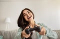 Happy Indian woman with joystick playing online video games, laughing and having fun at home. Weekend activities concept