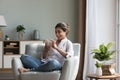 Happy Indian woman resting seated on cozy chair with smarthome