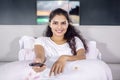 Happy Indian woman watching TV on bed at night Royalty Free Stock Photo
