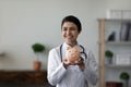 Happy Indian young female doctor showing piggy bank at camera Royalty Free Stock Photo