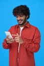 Happy indian young man using cell phone isolated on blue background. Royalty Free Stock Photo