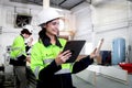 Happy industrial woman worker with helmet and safety vest holding tablet and inspecting wood raw material, coworker working with Royalty Free Stock Photo