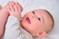 Happy infant baby boy pulls his leg into his mouth and smiles. Four month old child, close-up Royalty Free Stock Photo