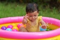 happy infant baby girl playing water splashing with colorful plastic balls in inflatable pool Royalty Free Stock Photo