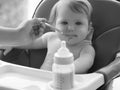 Happy infant baby girl spoon eats itself at home. little smiling girl sits in baby-chair and have a breakfast