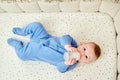 Happy infant baby lies in bed with a bottle of milk in his hands. Smiling child in a crib Royalty Free Stock Photo