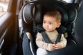 happy infant baby sitting in car seat and looking out of window, safety chair travelling