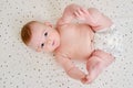 A happy infant baby with teething teeth in a diaper pulls his hand into his mouth. Funny child in a crib Royalty Free Stock Photo