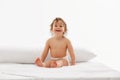 Happy infant, little girl with wet hair enjoying playtime, sitting on soft, white bedspread against white studio Royalty Free Stock Photo