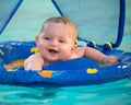 Happy infant playing in pool while sitting in baby float