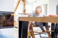 Happy infant sitting at dining table and playing with his toy in traditional scandinavian designer wooden high chair in