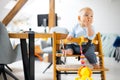 Happy infant sitting and playing with his toy in traditional scandinavian designer wooden high chair in modern bright