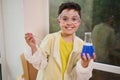 Happy, inspired Caucasian schoolboy pouring and combining blue chemicals during science experiment in chemistry lesson Royalty Free Stock Photo