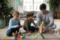 Happy interested small preschool boy and girl playing with dad.