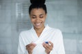 Happy interested young african mixed race woman using pregnancy test.