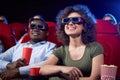 Happy international couple eating popcorn in cinema. Royalty Free Stock Photo