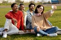 Happy international millennial students study, drink coffee, relax, sit on grass, taking selfie Royalty Free Stock Photo