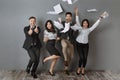 happy interracial business people standing at grey wall after successful