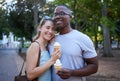 Happy, interracial and couple eating ice cream in a park on a date, anniversary or walk together. Love, smile and man Royalty Free Stock Photo