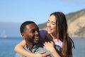 Happy interracial couple laughing on the beach on vacation Royalty Free Stock Photo