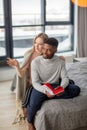 Happy interracial couple spending weekend together at home, relaxing with book