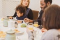 Happy interracial family with little children having breakfast in the morning, moments of daily life with Caucasian mother,