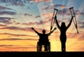 Happy invalids with crutches and in wheelchair sunset