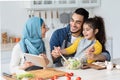 Happy Islamic Family Checking Recipe On Digital Tablet While Cooking In Kitchen
