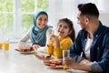 Happy islamic family with little daughter eating tasty breakfast together in kitchen Royalty Free Stock Photo